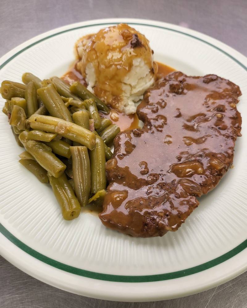Salisbury steak, made with fresh cubed steak served with mash potatoes, greenbeans, and a roll